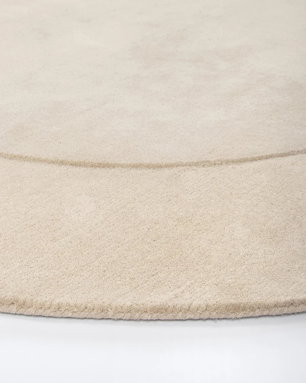 Edge detail of the Baya cream 'Form' curved floor rug