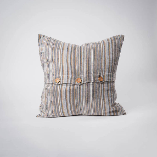 A front on view of a cushion with stripes in muted colours of ochre, slate, and red. The front is closed with three wooden feature buttons.
