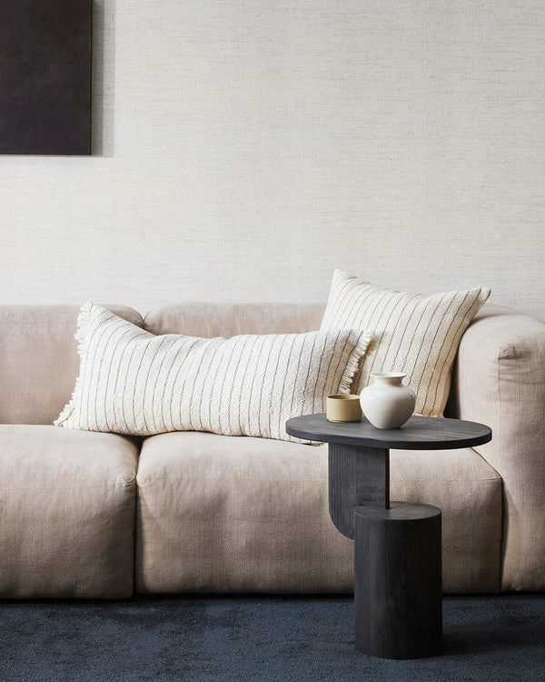 A chic interior scene featuring a cream coloured couch and two artisanal milk and midnight striped cushions by Baya NZ.