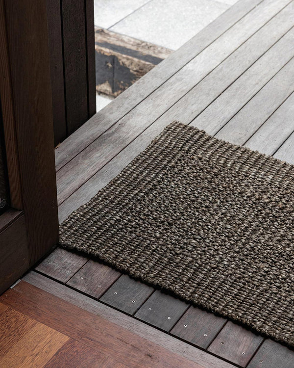 A doorway with a dark natural toned jute doormat. By Baya