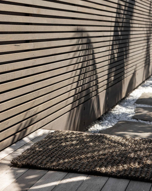 A sunny deck with a dark toned entrance mat, made with natural jute fibres by Baya