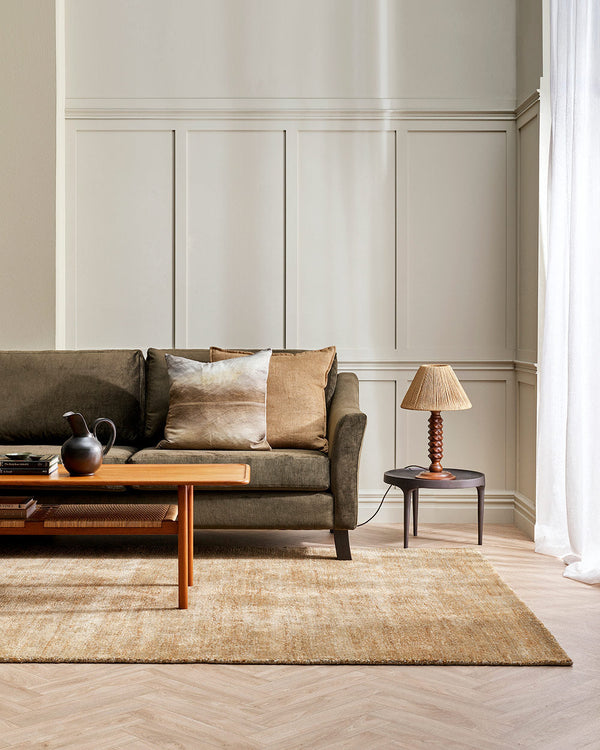 A sophisticated living room in warm cream tones with a soft floor rug in light sandy brown tones, made with bamboo silk and natural jute fibres by Baya