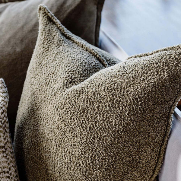 A close up image of the Kanso boucle cushion in Moss Green, the light hitting the texture.