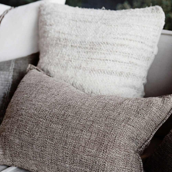 The Kenji cushion, a textured taupe weave, in lumbar on a stylish couch
