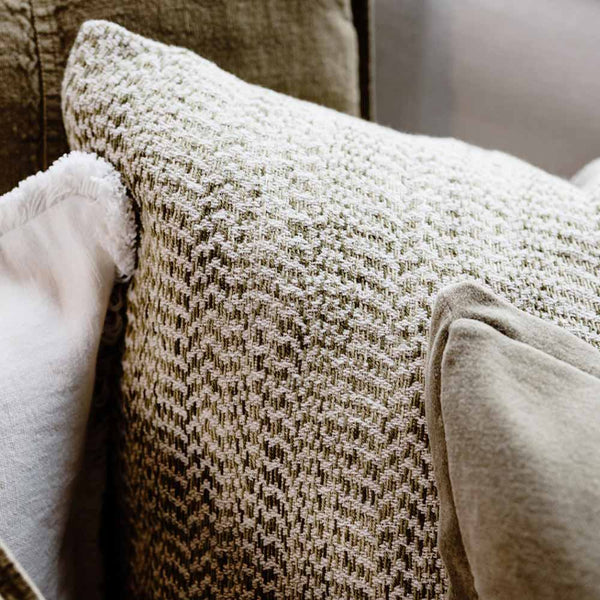 A close up view of the Midori cushion by Eadie, showcasing the beautiful textural green herringbone pattern