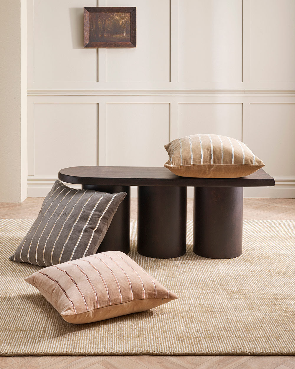 Several cushions by Baya on top of a warm toned beige 100% wool floor rug.