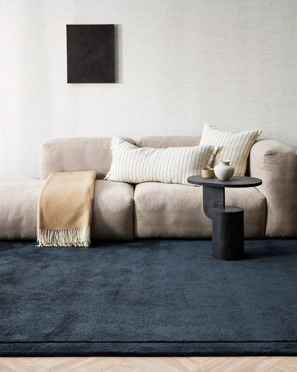 A cool toned lounge room with a luxurious deep cut pile floor rug in a shade of midnight blue in 100% NZ wool by Baya.