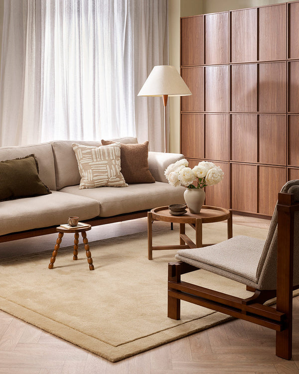 A stylish neutral living room with a beautiful floor rug in warm sand tones, with a deep pile and cut pile frame detailing along the edges, in 100% NZ wool by Baya.