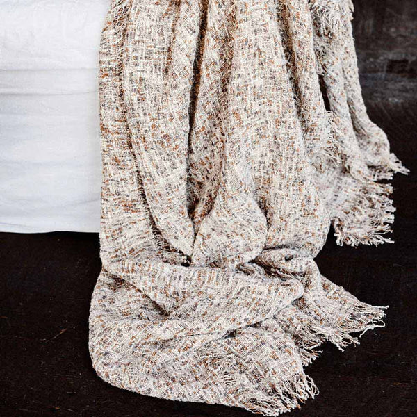 A 100% cotton textured throw blanket with fringe edges in a warm clay tone