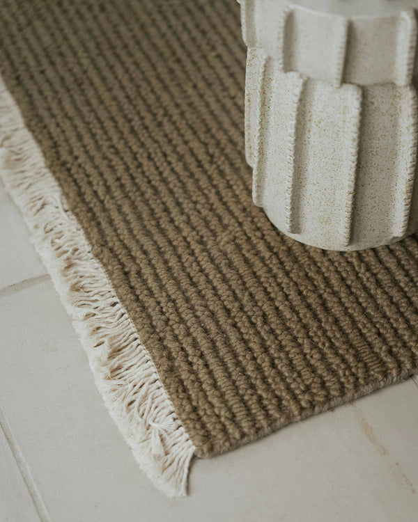Textured brown rug with white fringe on a light-colored floor
