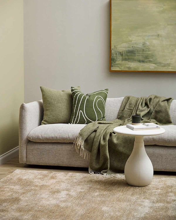 Warm beige floor rug styled with pillows and throw by Baya NZ in modern living room.