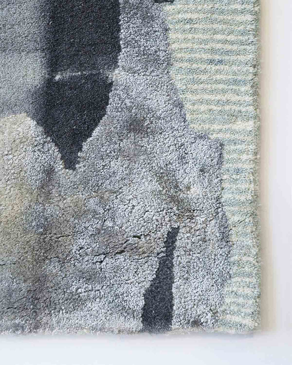 Close up of corner of Baya NZ Cape Brett rug. Cool greys and blues hand tufted in a swirling pattern.