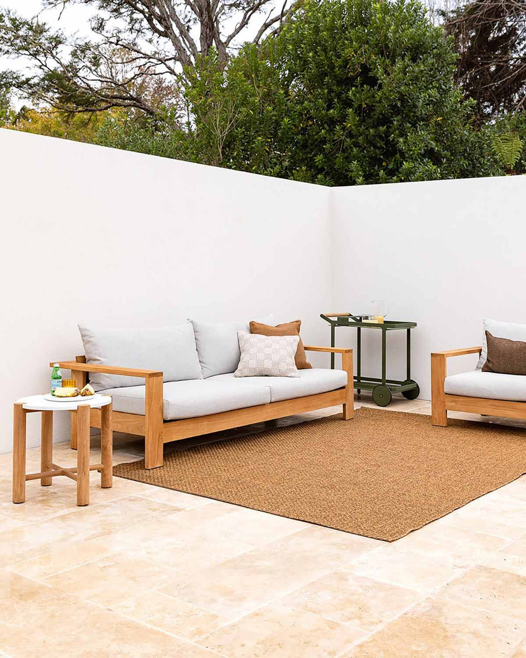 A warm brown basketweave rug by Baya NZ, shown in a sophisticated modern courtyard with couches.