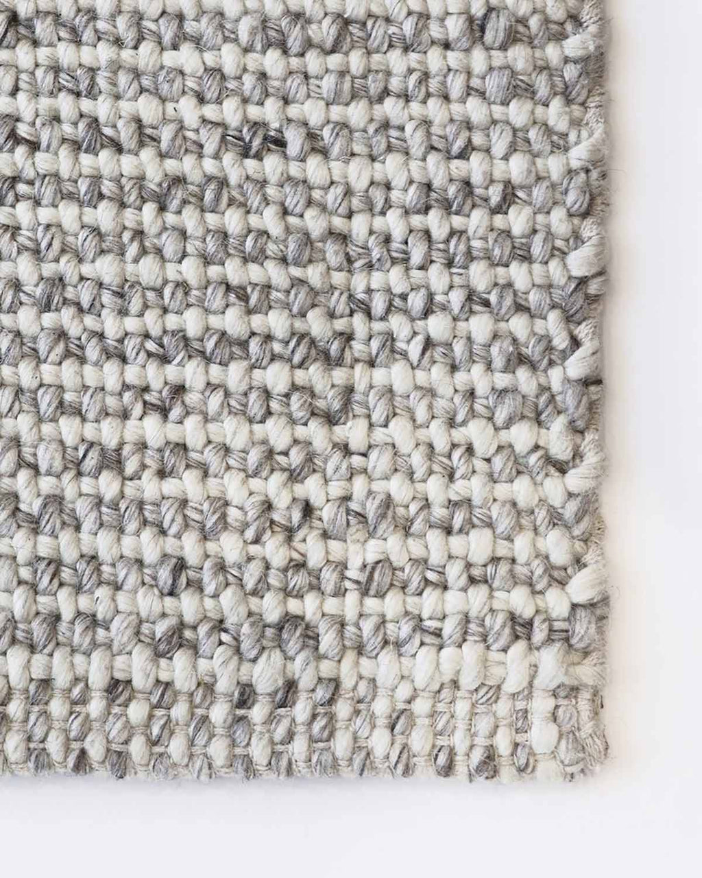 Top-down view of the corner of a Baya NZ rug, showing off the cool-toned weave of the fabric