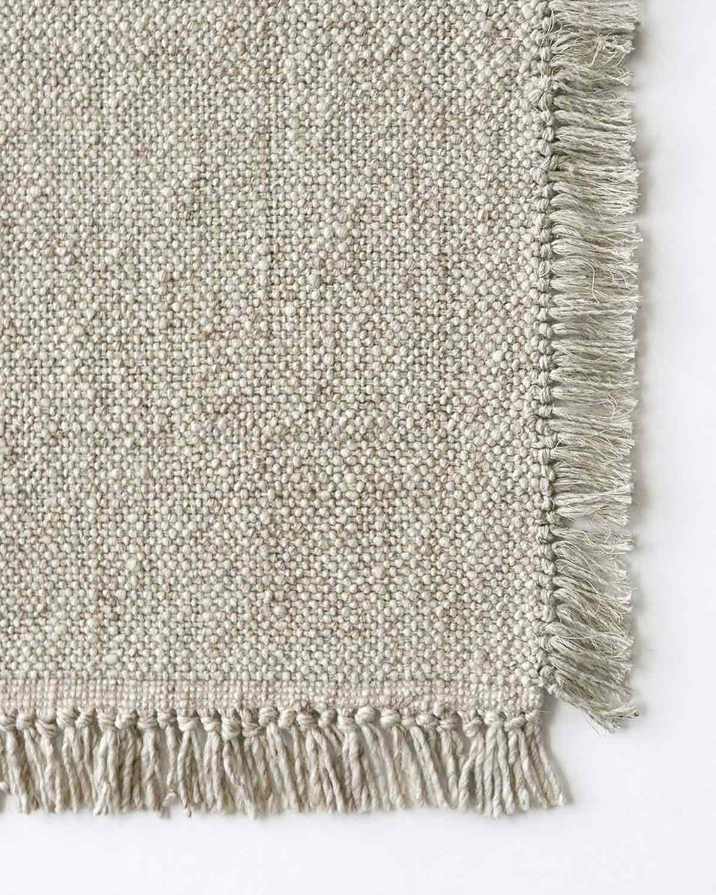 A top-down view of the corner of the Ulster rug by Baya NZ, showing off its fringed edges.