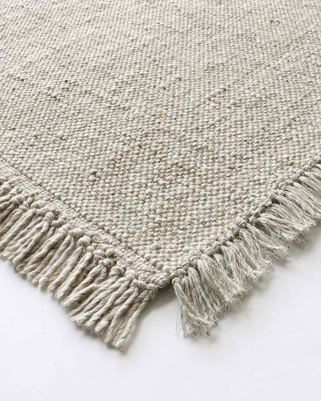 A detailed view of the corner of the Ulster rug by Baya NZ, showing off its fringed edges.