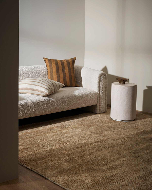 Brown floor rug and striped cushions, by Baya NZ, in a modern living room.
