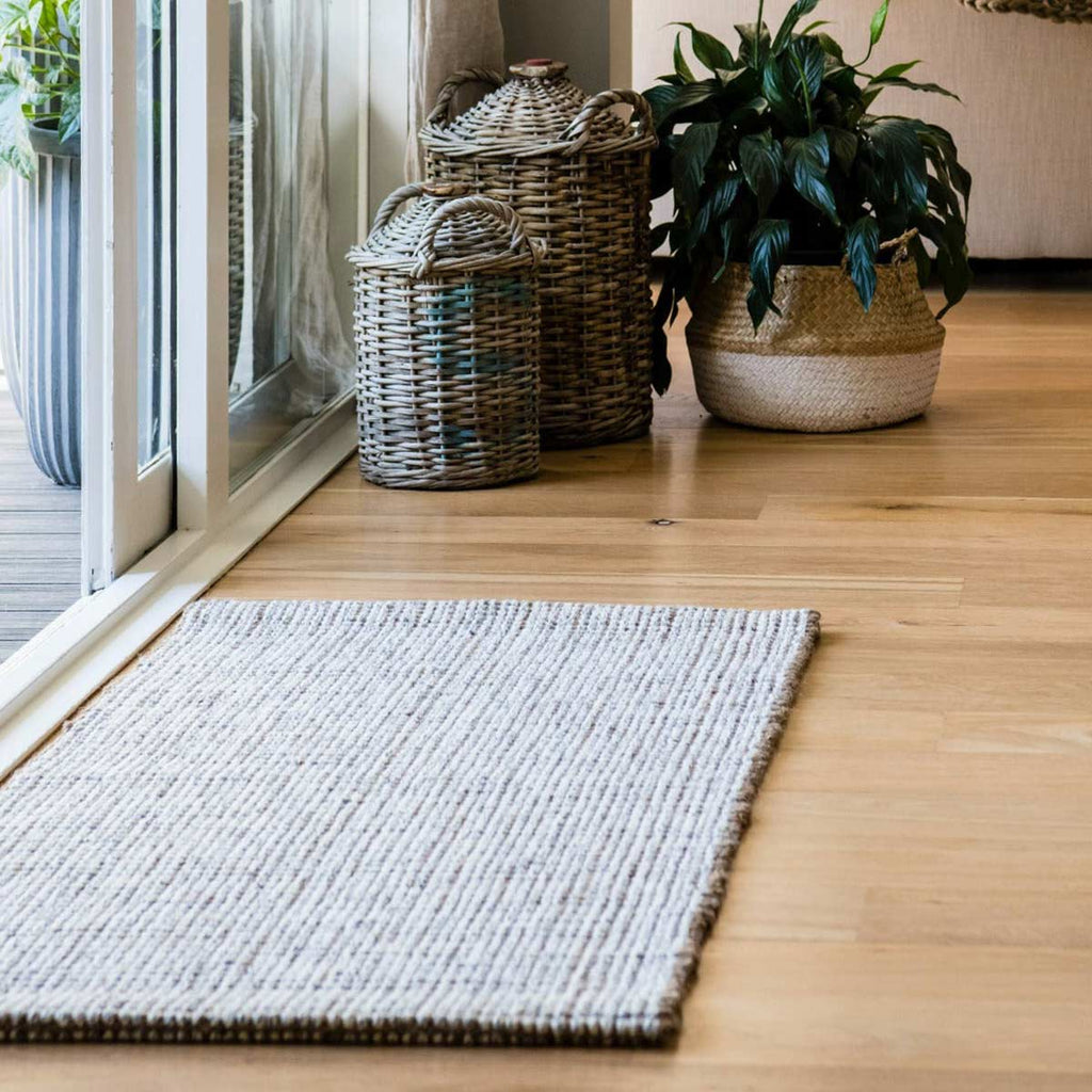 An entranceway with a doormat made with a blend of white wool and natural brown jute fibres.