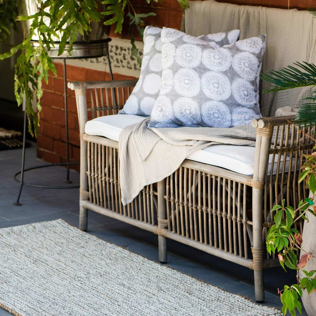 A cream and brown floor runner in front of a deckchair on a patio.