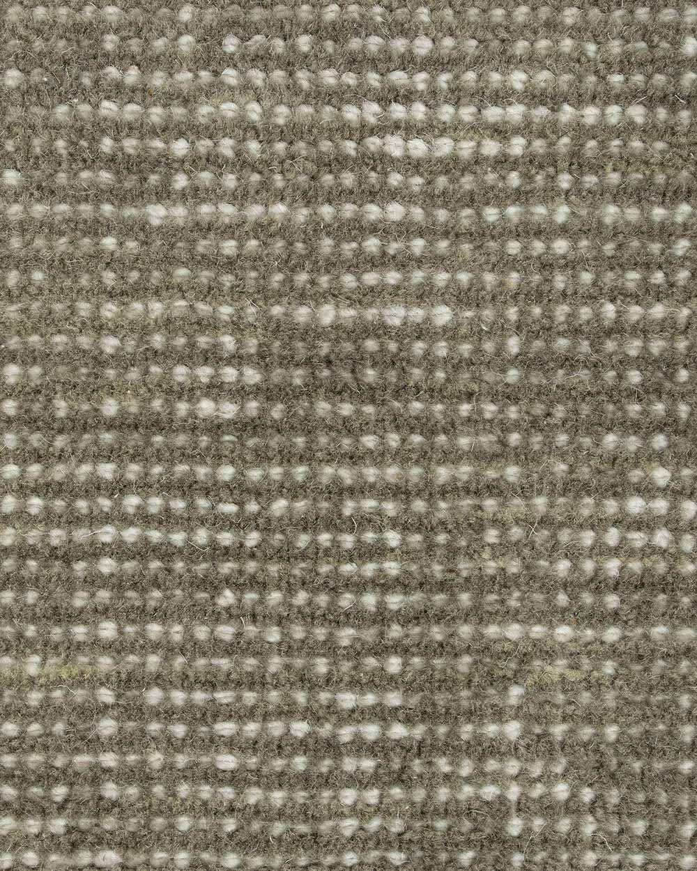 A close up image of a handloomed sage green toned floor rug in 100% New Zealand Wool by Baya