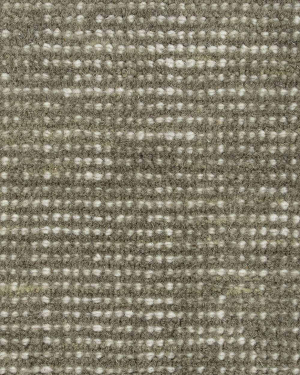 A close up image of a handloomed sage green toned floor rug in 100% New Zealand Wool by Baya