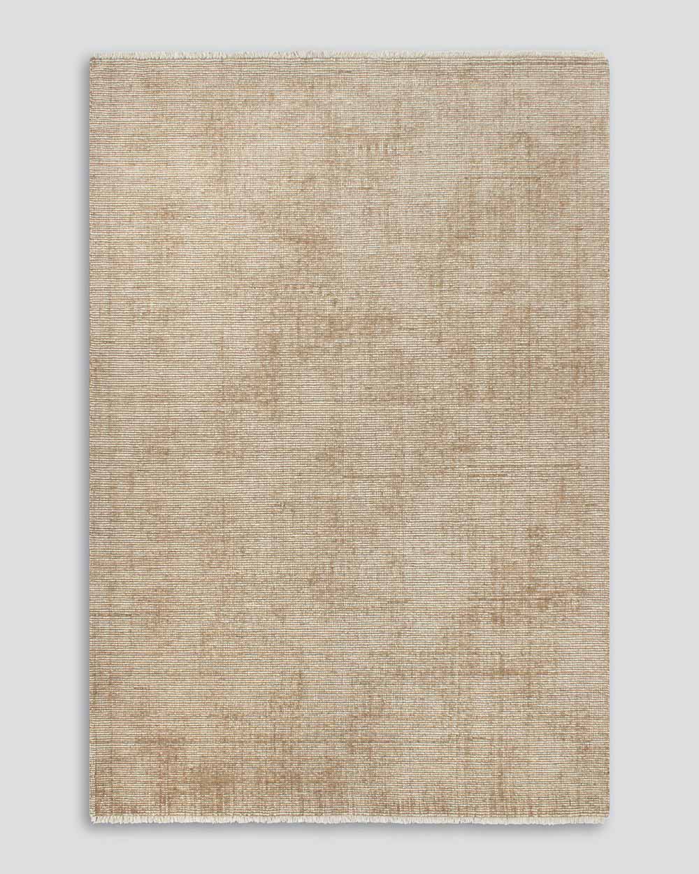 A full image from above of the Corbett floor rug in the shade Honey, a lightly distressed contemporary warm beige, with cream detailing and a short creamy fringe. By Baya