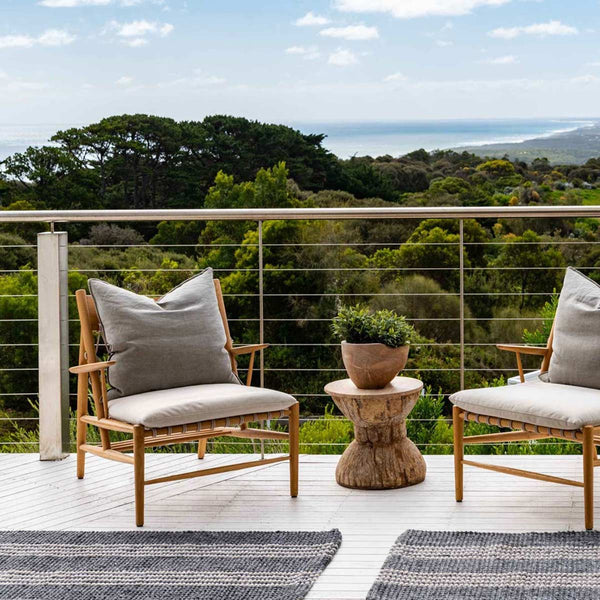 A deck with an ocean view and two slate grey oversized floor mats made from recycled bottles, with a cream stripe pattern.