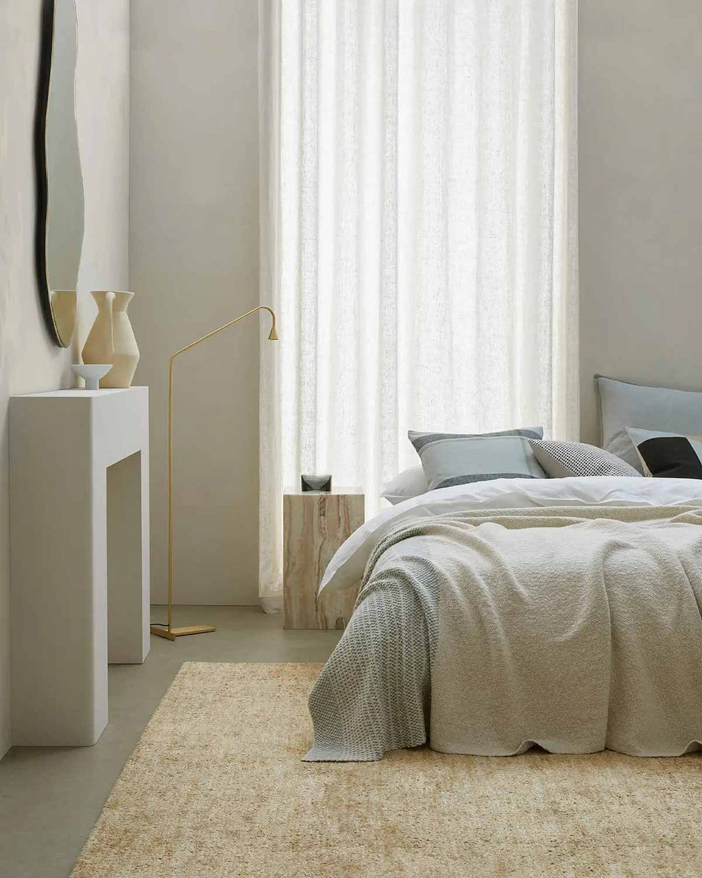 A calm looking modern bedroom, with a bed draped with a cotton knit throw blanket by Weave Home.