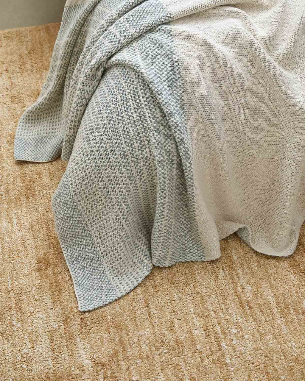 A close up image of Laurel shade of Sonoma throw blanket by Weave Home, draped over a bed.