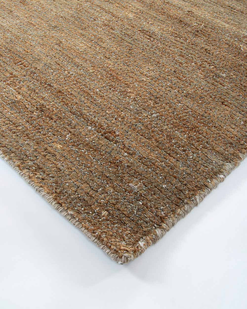 A corner image of the Fairbanks floor rug in shade Sand, a deliciously warm toned brown handwoven piece.