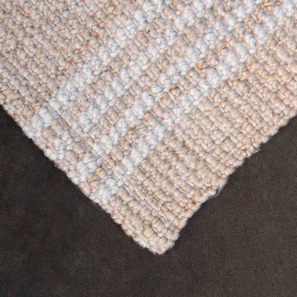 A detailed view of the corner of a neutral warm beige toned floor mat, with crisp off-white striping.