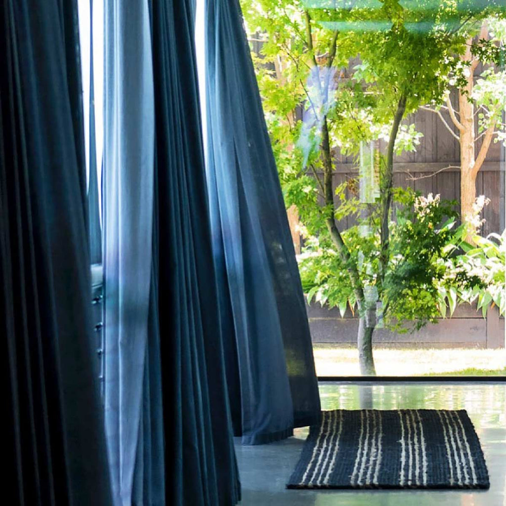 A doorway with an entrance mat in black jute with natural brown striping.