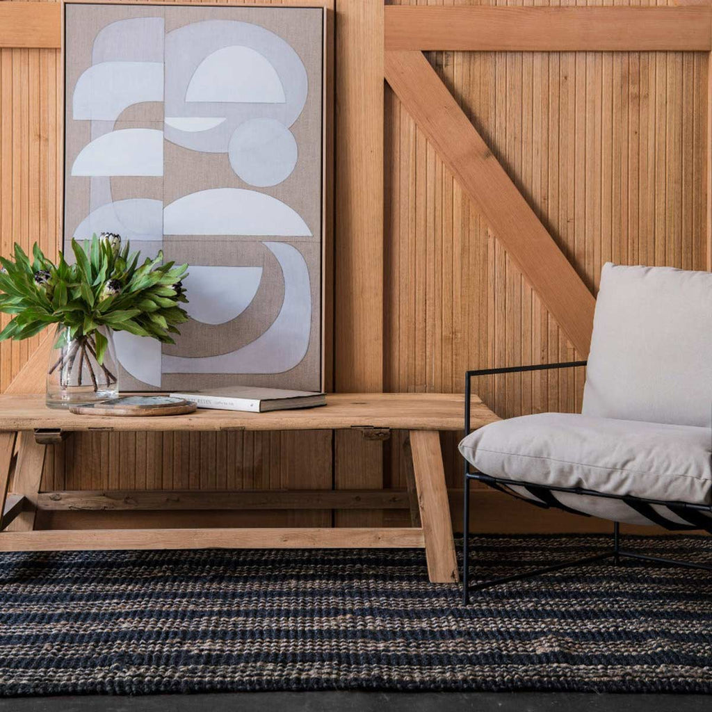A sitting area with an artisanal hand knotted jute floor rug in deep graphite black with a natural brown stripe pattern.