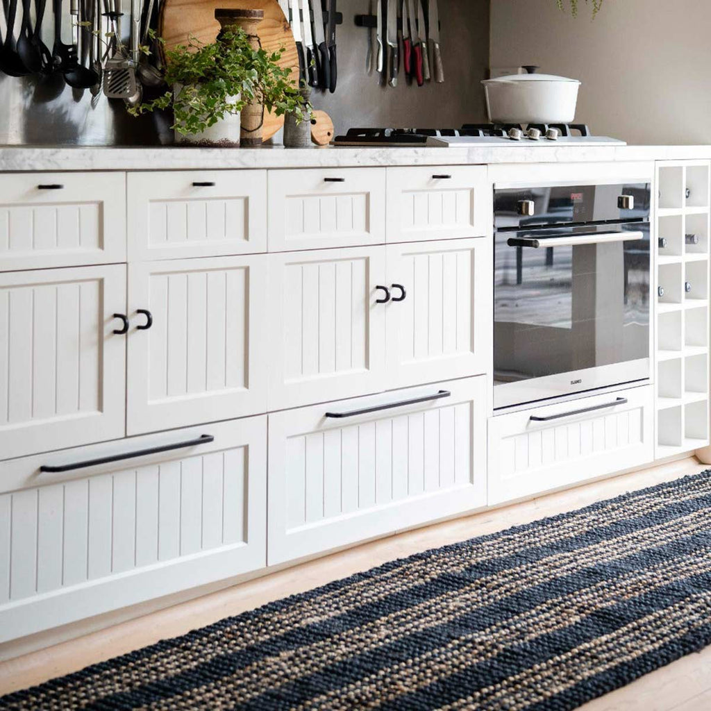 A white toned bohemian style kitchen with a contrasting black and natural jute striped floor runner rug.