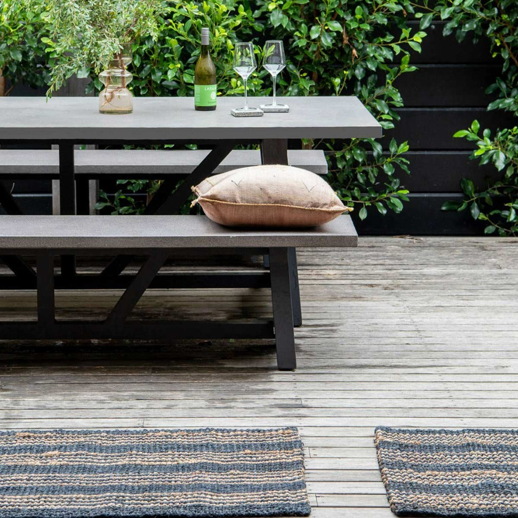 A deck area with two oversized black jute mats with brown striping.