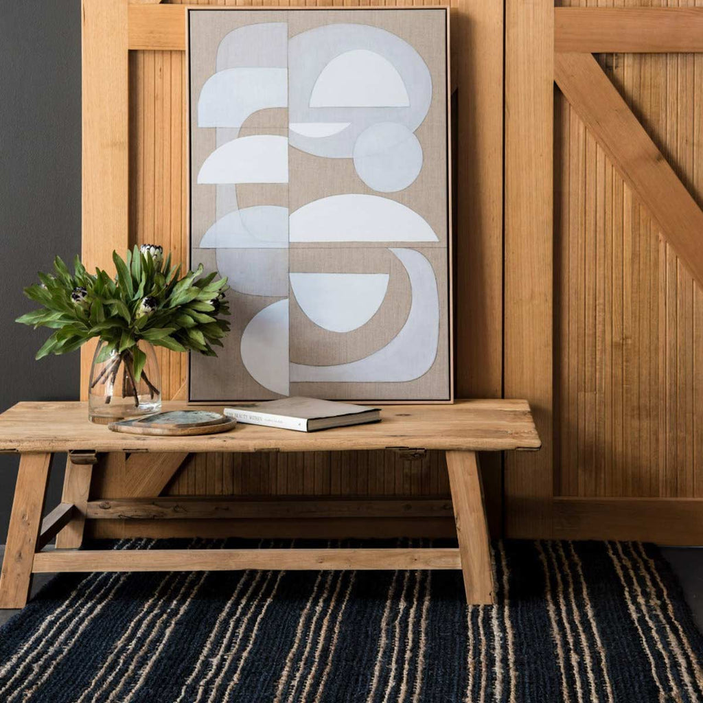 An end table with a black and natural brown striped jute fibre rug underneath it.