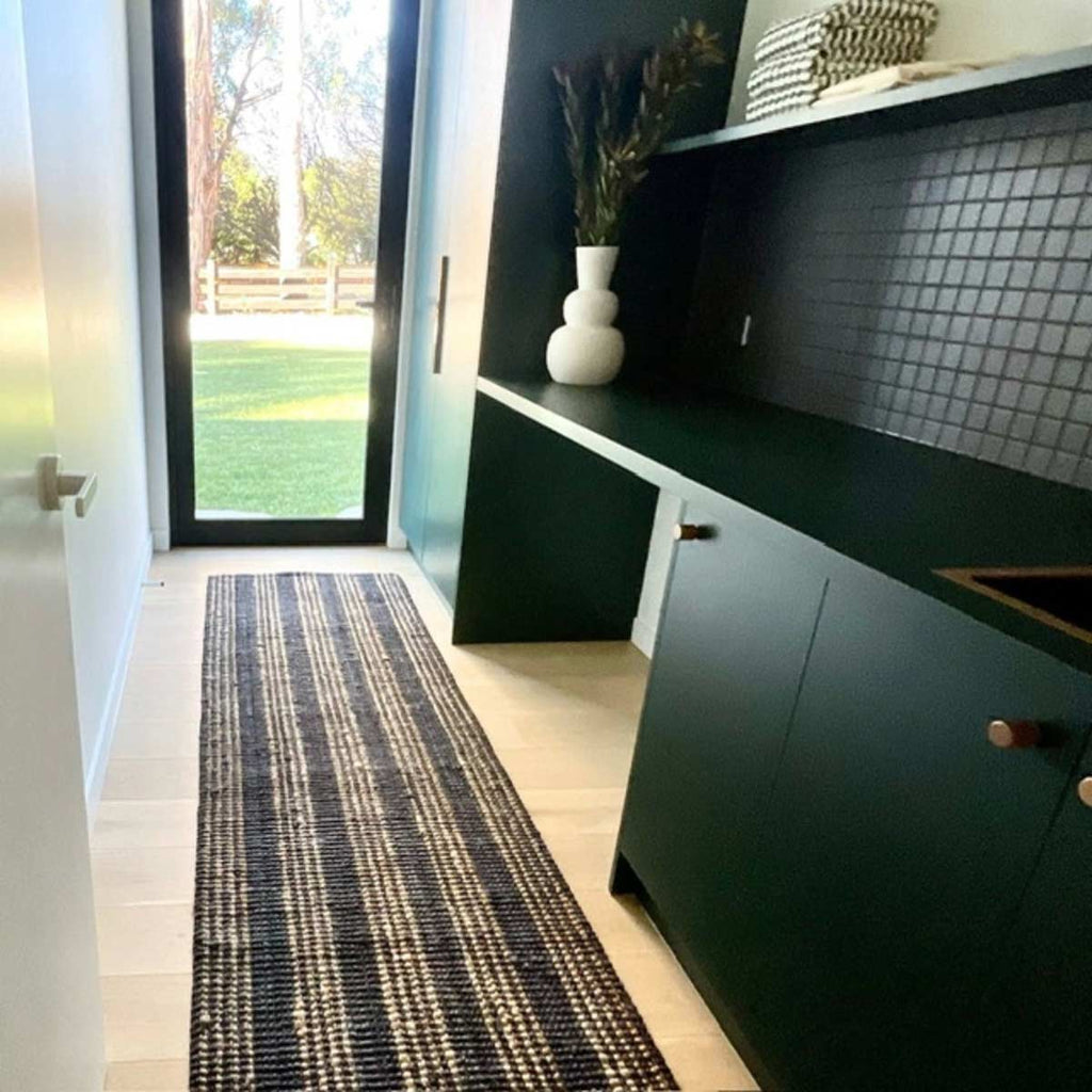 A modern kitchen in minimalist black tones with a black and natural jute striped floor runner.