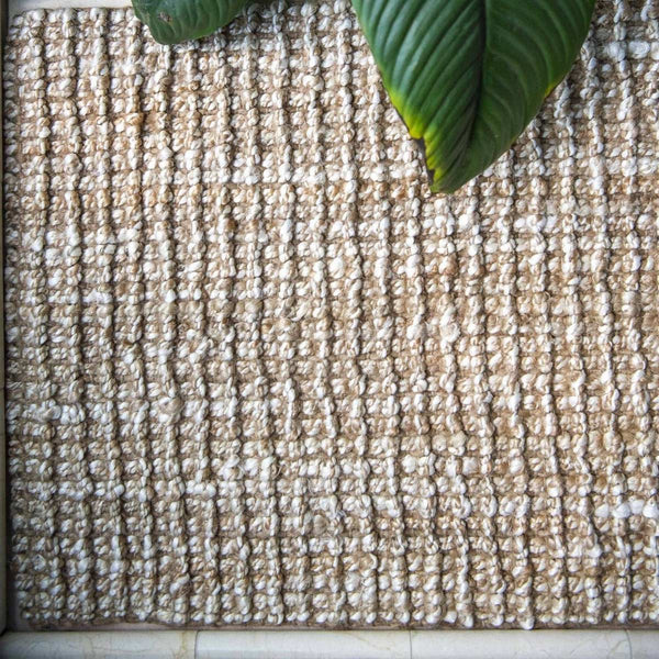 A detailed view of the hand knotted texture and subtle whitewashed jute floor rug.