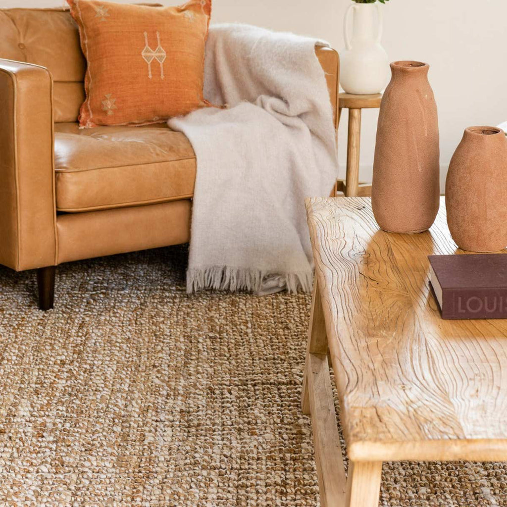 A cheery sitting area in orange tones, with a natural brown textural jute floor rug.