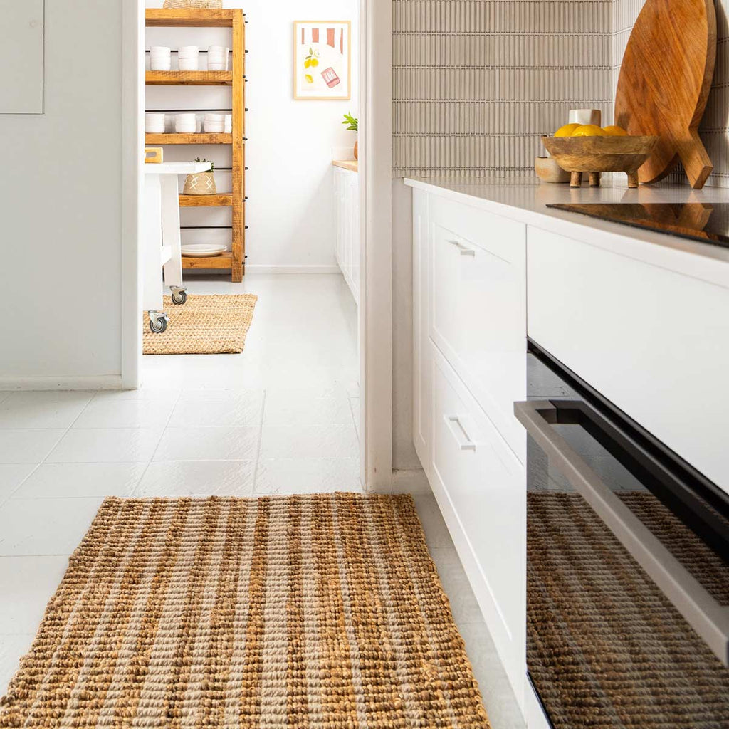 A kitchen with two rugs of different sizes, both subtly striped in natural brown and white tones in a blend of wool and jute.