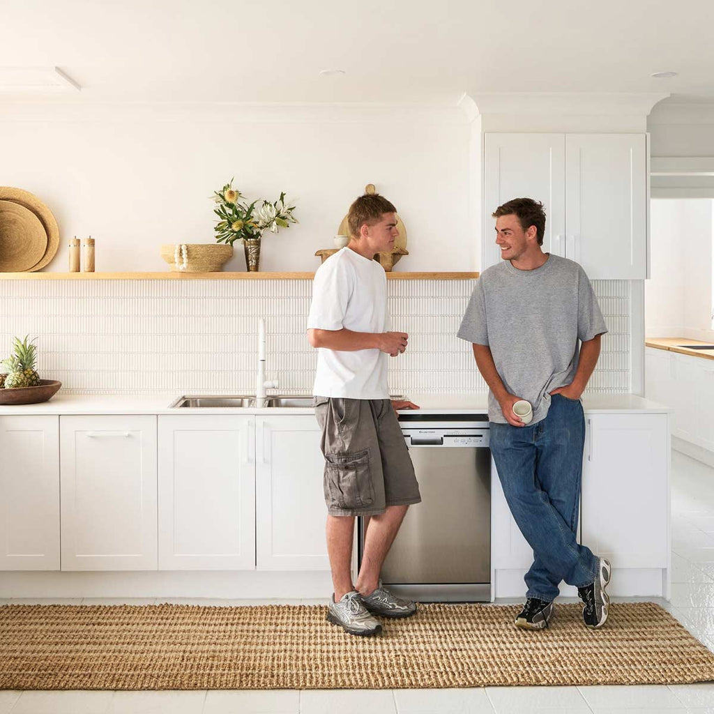Two men stand in a minimalist kitchen, with a hand knotted striped jute and wool fibre floor runner in natural jute tones.