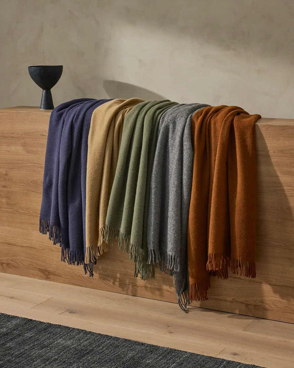A multitude of throw blankets by Weave Home, including the shade Navy, a deep blue.