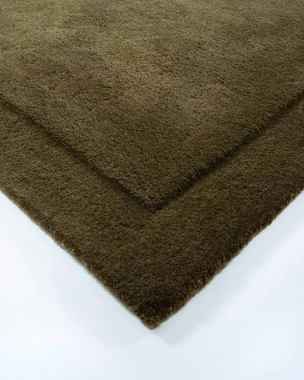 The corner of the Norfolk rug in Olive by Baya. The minimalist cut-pile border adds interest to this stunning piece.