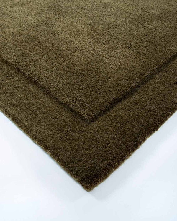 The corner of the Norfolk rug in Olive by Baya. The minimalist cut-pile border adds interest to this stunning piece.