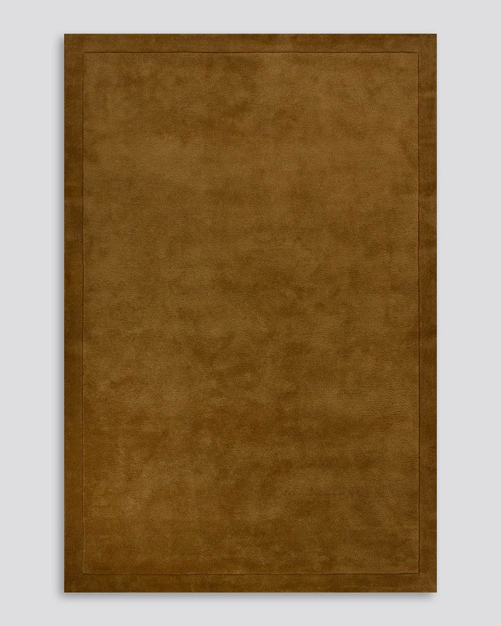 A full image of the Norfolk floor rug in the shade Chocolate. The border of the rug is cut-pile in a minimalist and refined design, and the pile of the rug's centre is luxuriously deep.