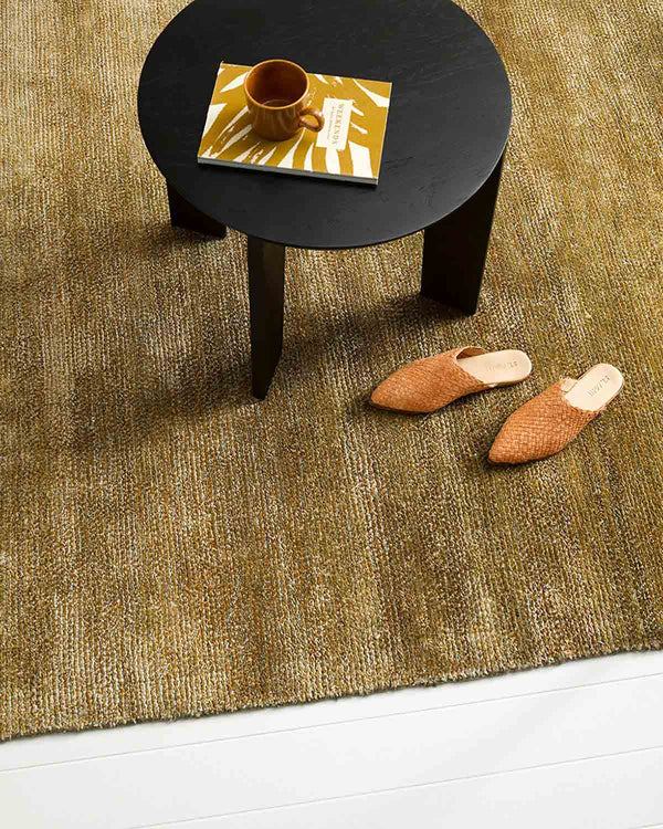 Brown floor rug by Baya NZ, seen from above, under a coffee table, in a modern living room.
