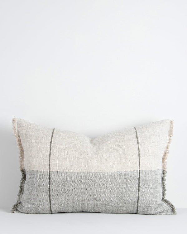 A linen lumbar cushion in shades of sage and cream, with two stripes parallel to one another and soft fringe edges. By Baya