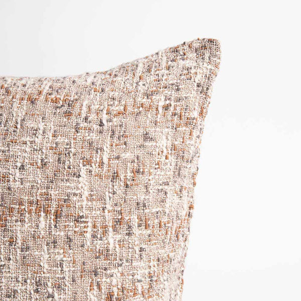 The corner of a richly textured slub weave cushion, with interwoven clay, midnight blue, and off-white threads