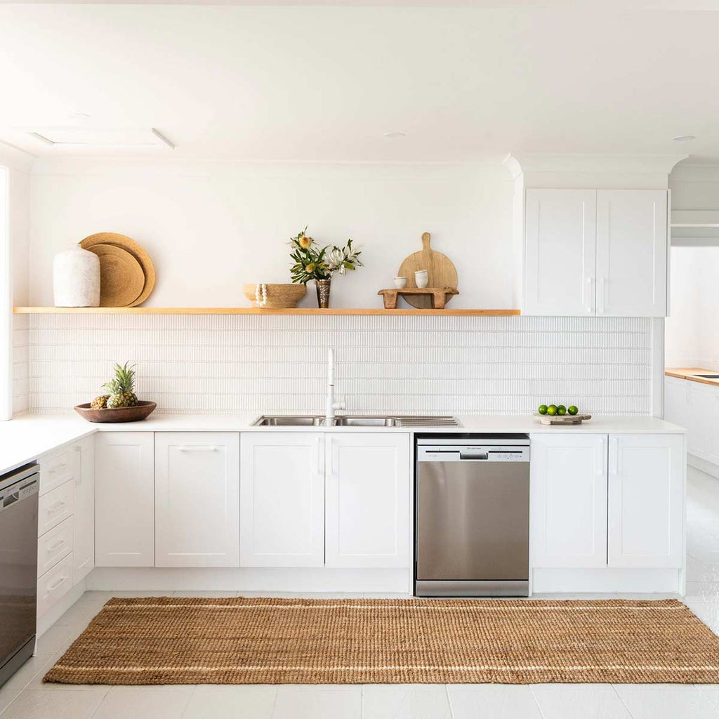 A minimalist white kitchen with a natural jute brown floor runner with two whitewashed white stripes.
