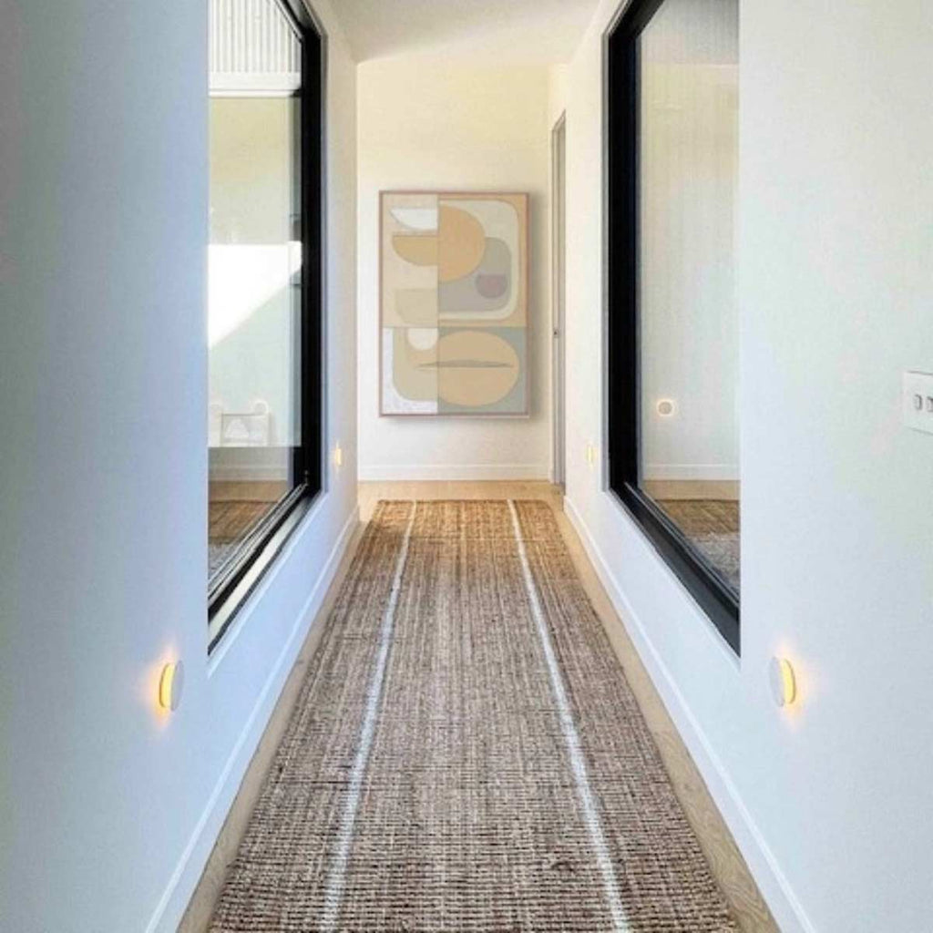 A long hallway with a floor runner made with natural jute and with two white stripes.